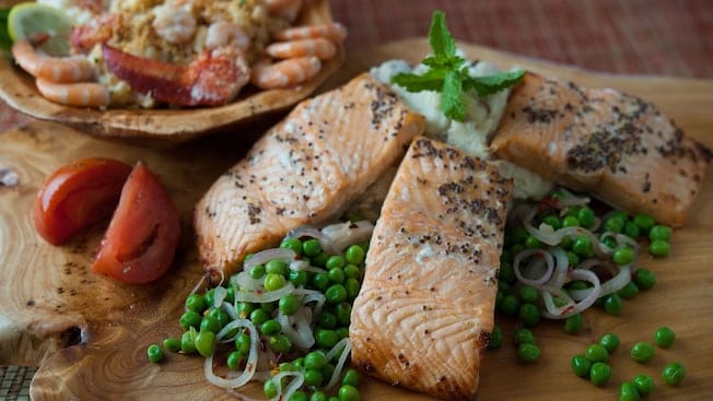 Three pieces of salmon with peas and onions and a bowl of lobster-and-shrimp mac n' cheese