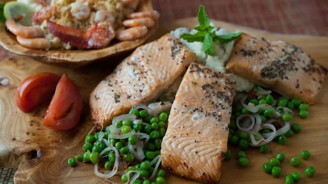 Three pieces of salmon with peas and onions and a bowl of lobster-and-shrimp mac n' cheese