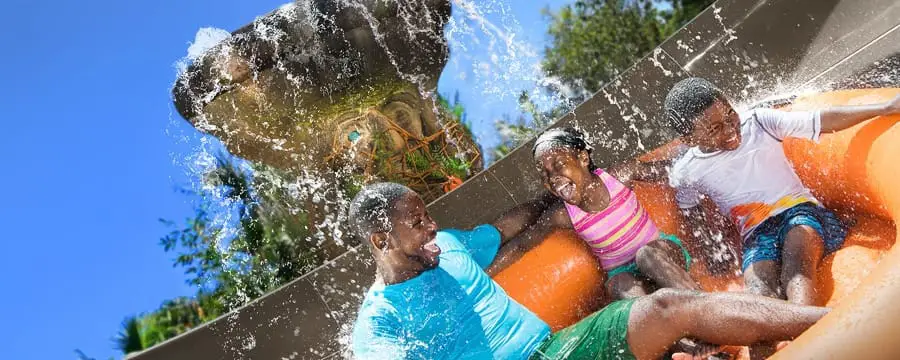 A father, son and daughter get splashed while riding on a family raft at Miss Adventure Falls